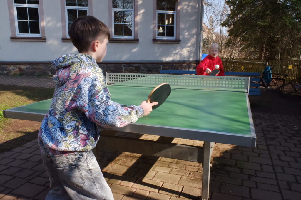 Zwei Jungen spielen im Freien Tischtennis.