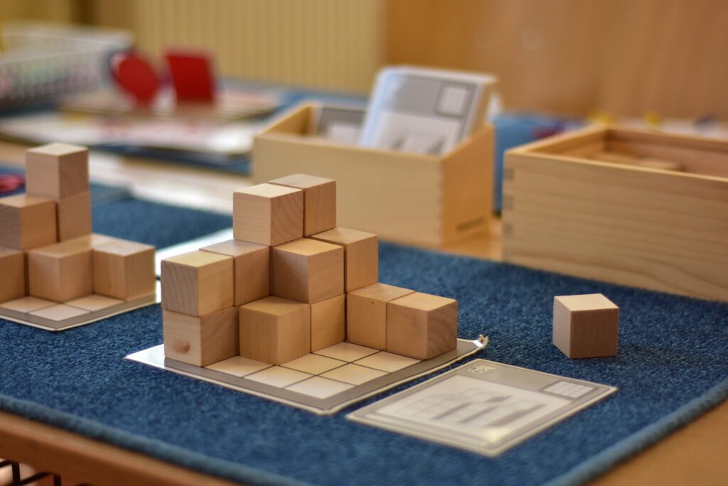 Nach einer Vorlagenkarte aus Holzwürfeln gebautes Muster – Montessori-Baumaterial.